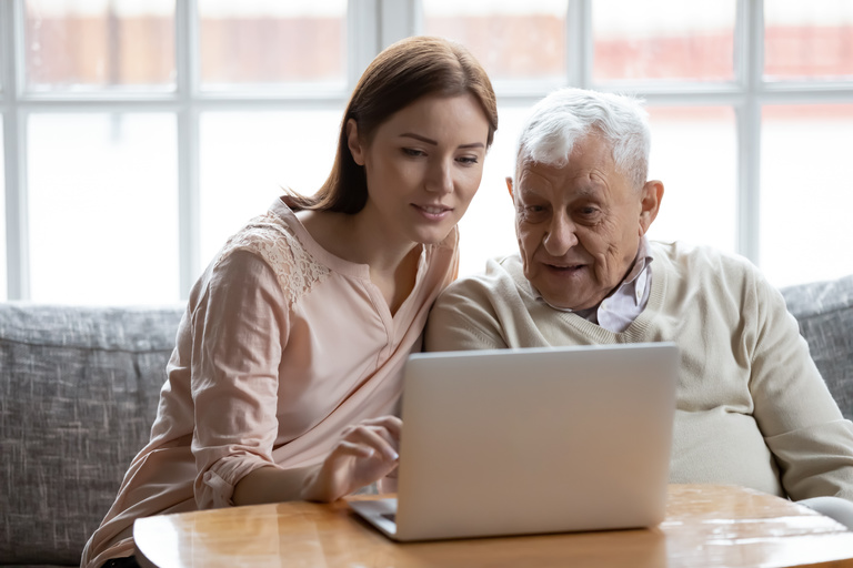 Älterer Mann bekommt Hilfe bei der Nutzung von einem Laptop