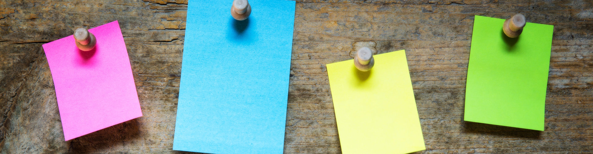Verschiedenfarbige Notizzettel die an einer Holzwand hängen